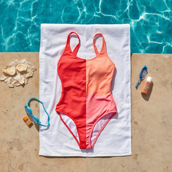 A bright summer poolside scene featuring a high-quality swimsuit carefully laid flat on a white towel in the shade. Nearby are fresh water, sunscreen, and swimming goggles. The swimsuit looks vibrant and well-maint.jpg